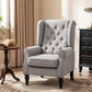 Gray wingback accent chair with button-tufting, rolled arms, and dark turned legs.
