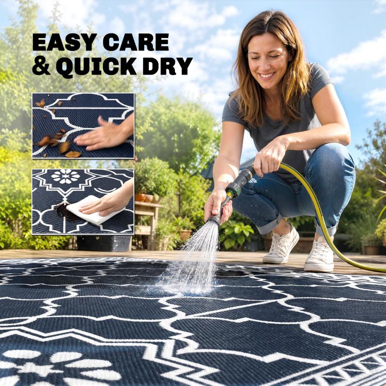 Outdoor rug sprayed with water from a hose, showing white geometric pattern on dark base