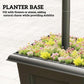 Rectangular black planter base filled with colorful flowers beneath a solar post