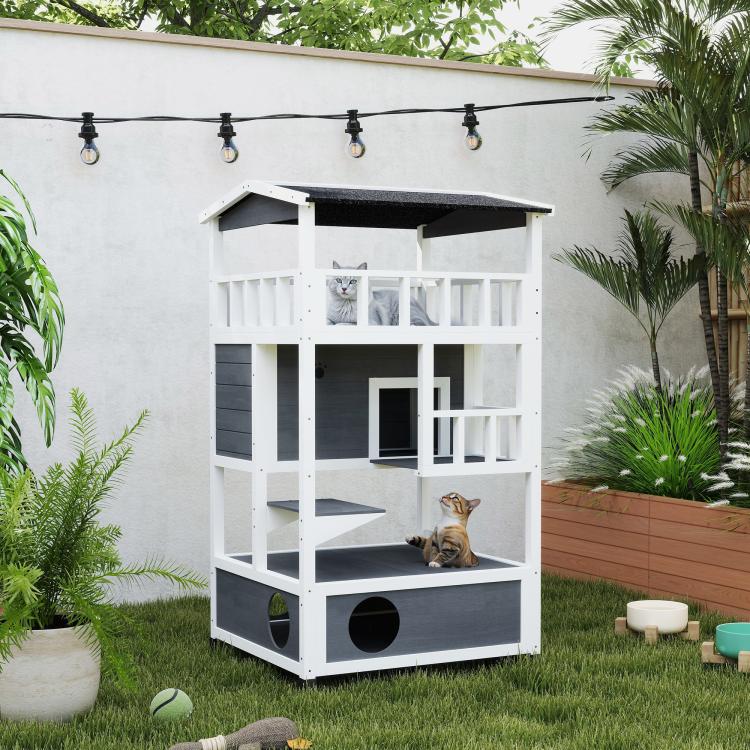 Outdoor white-and-gray wooden cat house with dark roof, balcony rails, and round openings