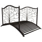 Dark bronze metal garden bridge with decorative scrollwork guardrails and grate deck