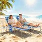 Pair of blue striped folding chaise lounge chairs with side tables on beach sand