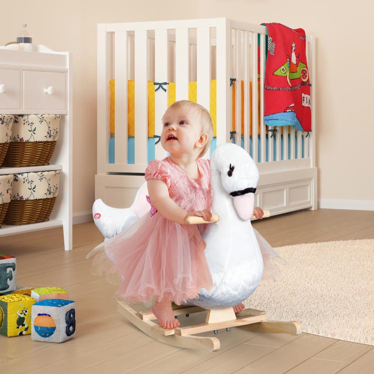 Baby standing on white plush swan rocking horse with pink padded seat