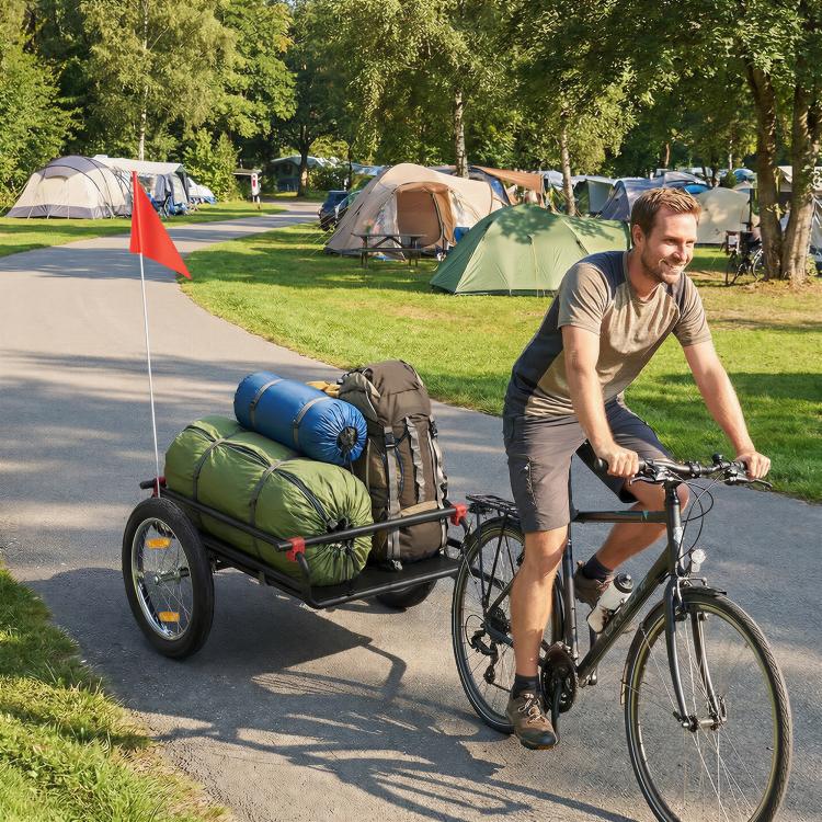 Bike cargo trailer with green and rolled gear in the black bed, on pneumatic wheels