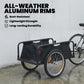 Black bike cargo trailer with open fabric bed, 16-inch pneumatic wheels, red safety flag on wet ground