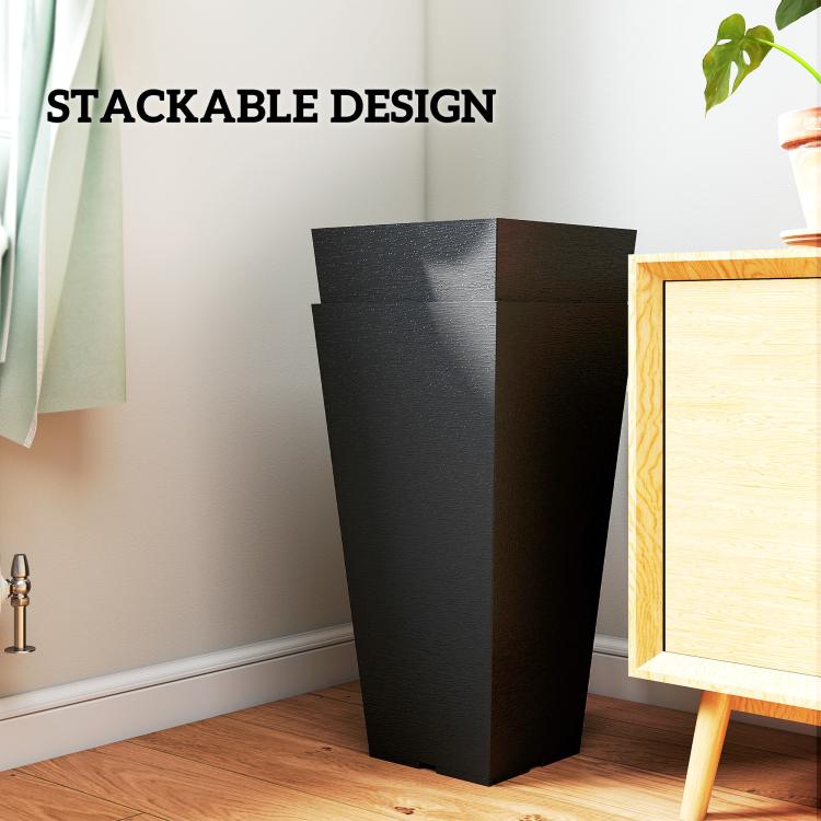 Tall black plastic planter with stackable design, shown indoors on a wooden floor