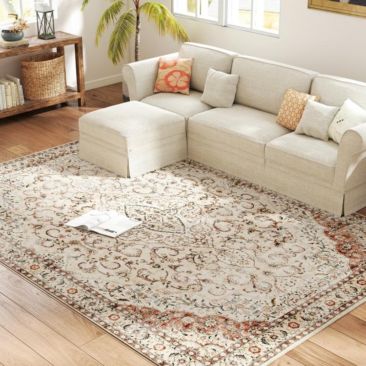 Cream classical floral area rug with brown and rust accents under a sofa in a room
