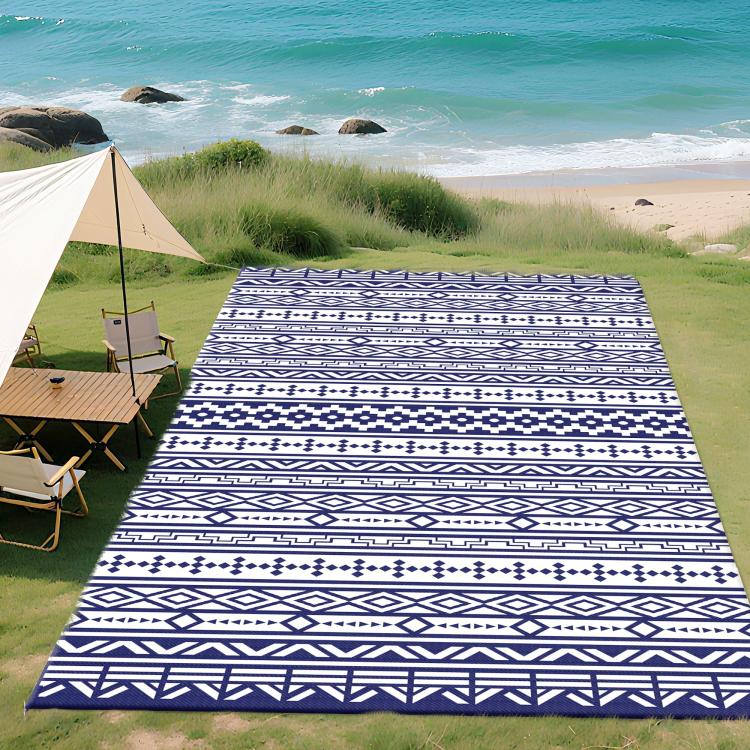 Reversible outdoor rug with blue and white geometric pattern, laid flat on grass