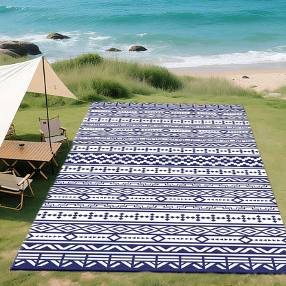 Reversible outdoor rug with blue and white geometric pattern, laid flat on grass