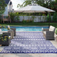 Reversible outdoor rug with blue and white geometric pattern, laid on patio