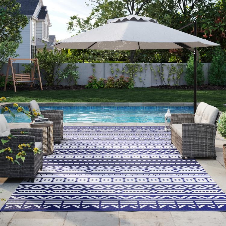 Reversible outdoor rug with blue and white geometric pattern, laid on patio