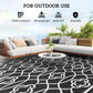 Outdoor reversible rug with black background and white clover trellis pattern