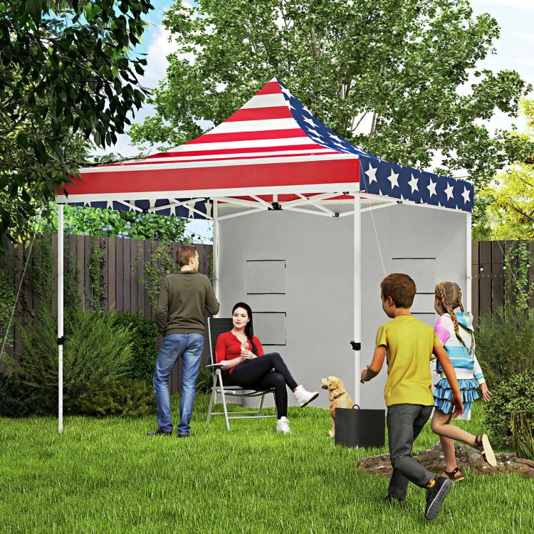 American flag pop-up canopy tent with gray sidewalls in a backyard lawn