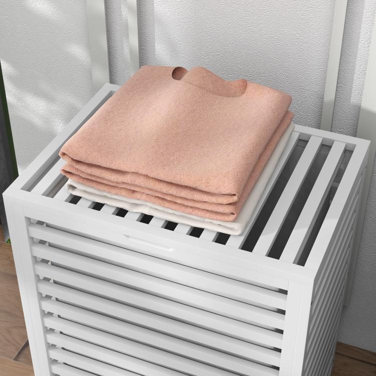 White slatted bamboo laundry hamper top with stacked folded towels