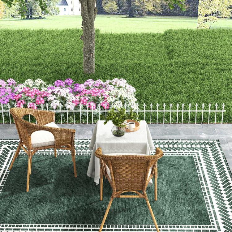 White metal garden fence border with chairs, flowers, and a patio walkway