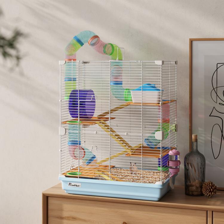 Light blue hamster cage with white wire walls and colorful play tubes on a tabletop