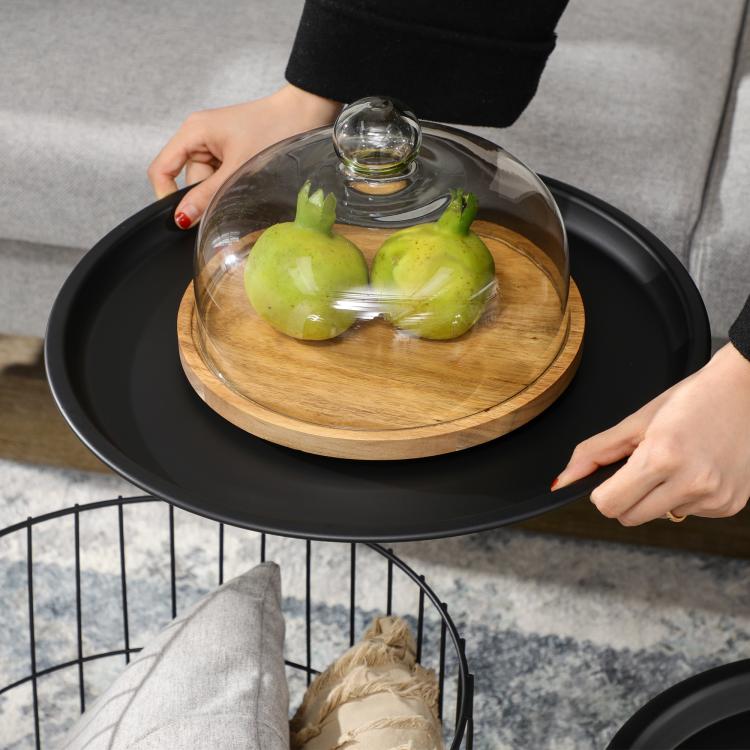 Black wire basket coffee table with round dark top and wood insert holding a glass dome
