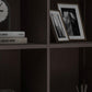Dark brown cabinet shelf with framed photos and small book spines inside