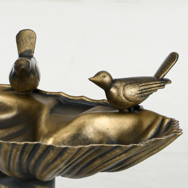 Close-up of bronze shell basin with bird statue accents and ridged bowl details