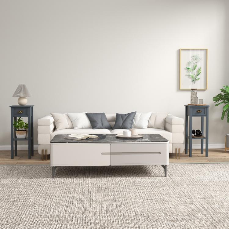 Gray side table with drawer and lower shelf, styled beside a sofa.