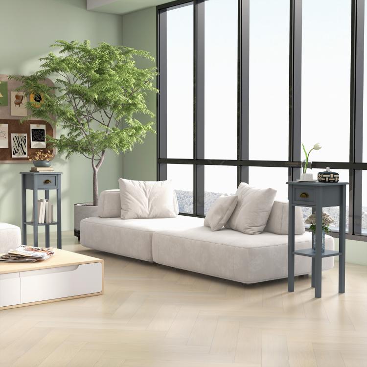 Gray side table with drawer and open lower shelf, shown next to a windowed living space.
