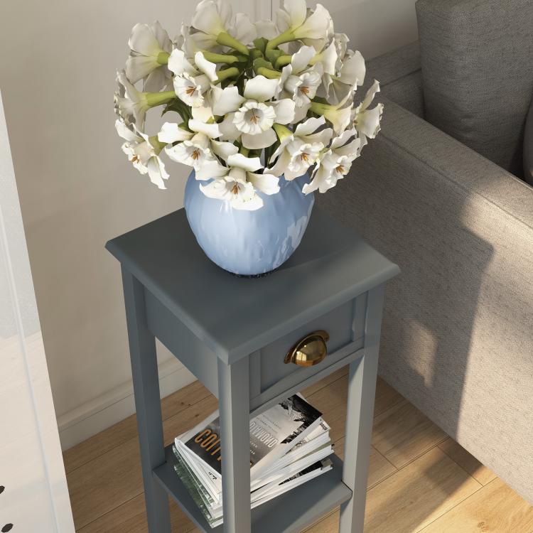 Gray side table with drawer and lower shelf, holding a vase and decor.