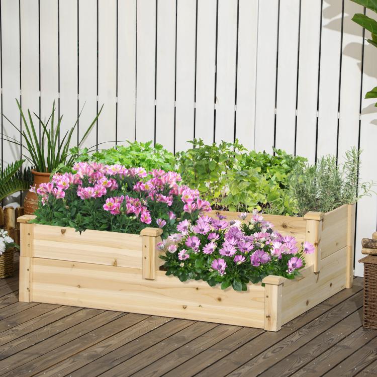 Three-tier raised wooden planter box with pink flowers and leafy green plants