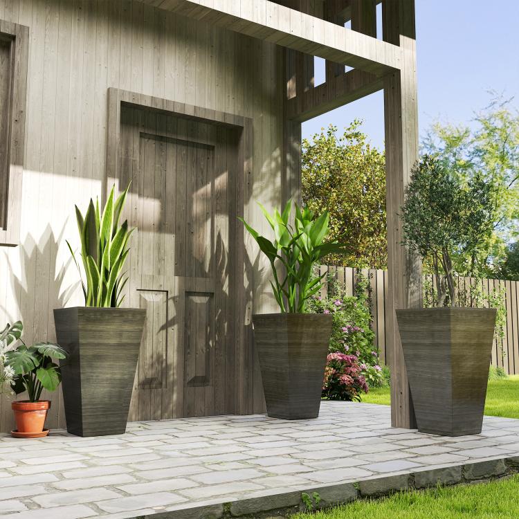 Three tall dark brown wood-look plastic planters on a patio with tall leafy plants