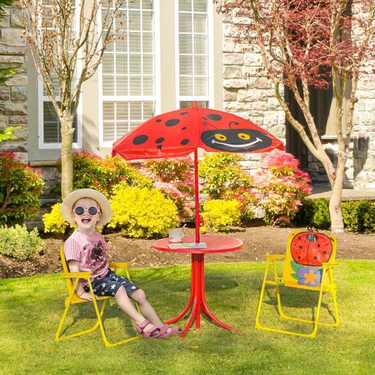 Ladybug red kids table with two yellow folding chairs and umbrella in a backyard