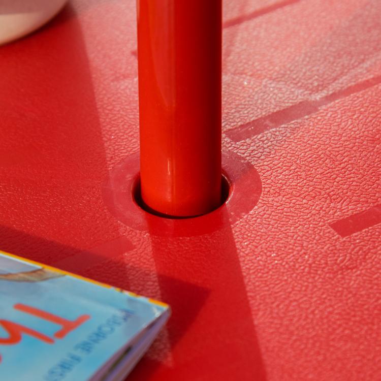 Close-up of red umbrella pole base on a textured round table top