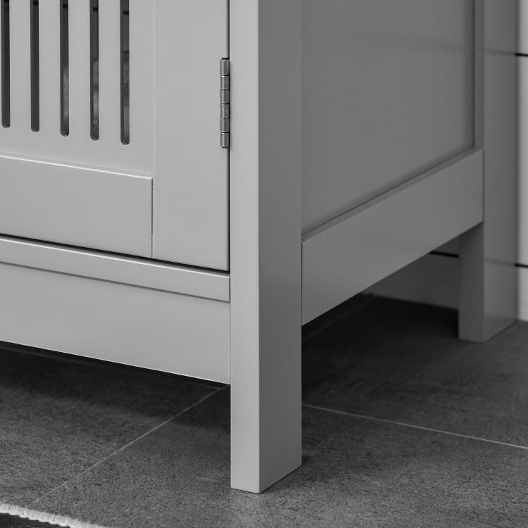 Close-up of grey cabinet side panel, hinges, and lower base leg on bathroom floor.
