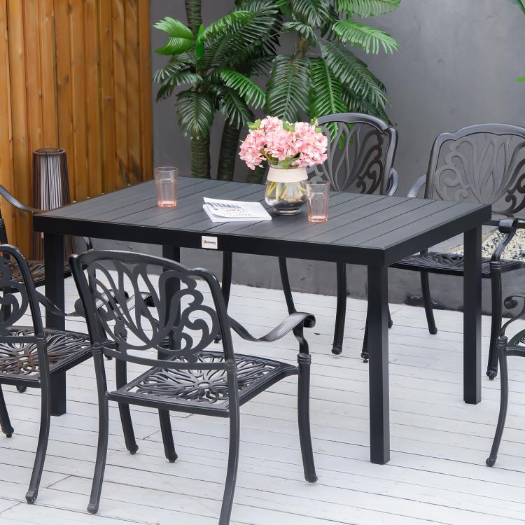Outdoor dining table with black tabletop and metal chairs in front of it