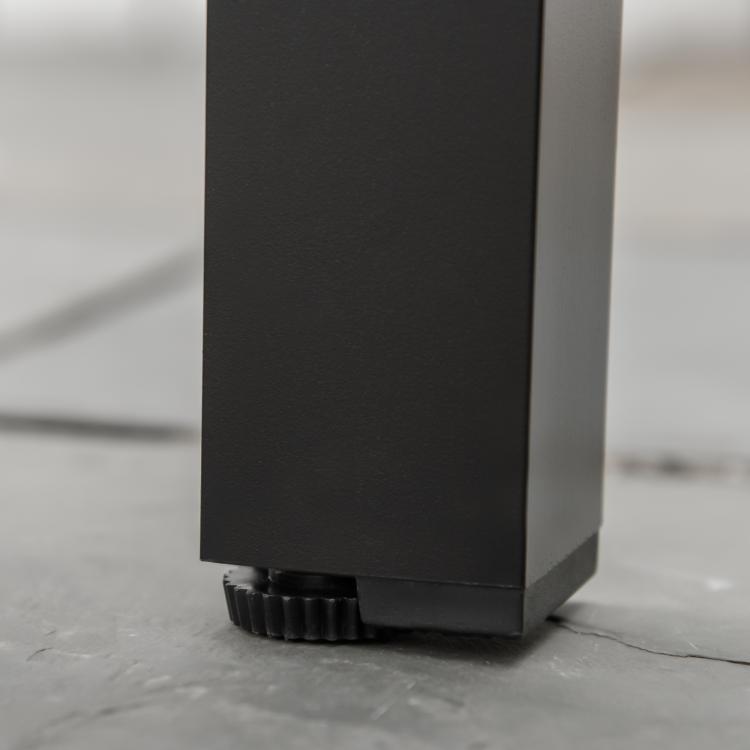Black metal table leg with textured adjustable foot pad on the floor