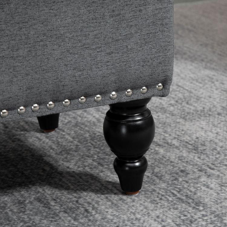 Gray upholstered storage ottoman with button-tufted side and black turned legs