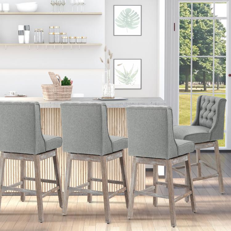Set of 2 gray upholstered bar stools with tufted backs, wooden legs, and footrests.