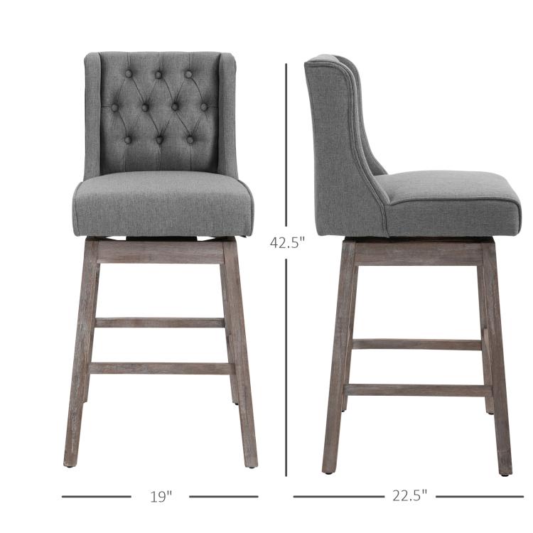 Gray bar stools set with button-tufted backs, padded seats, and wood legs with footrests