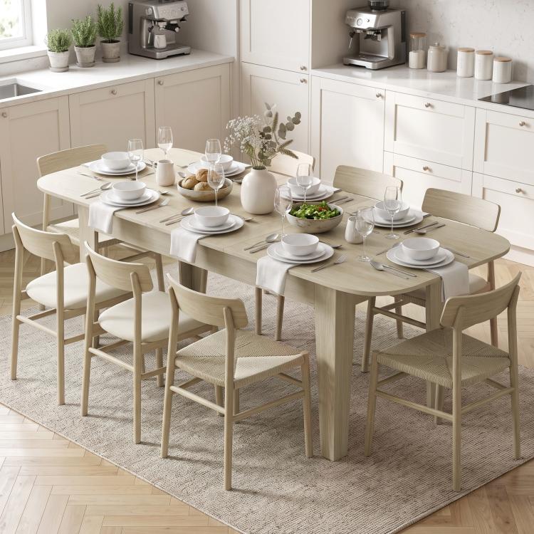 Light oak extendable oval dining table with dining chairs and place settings