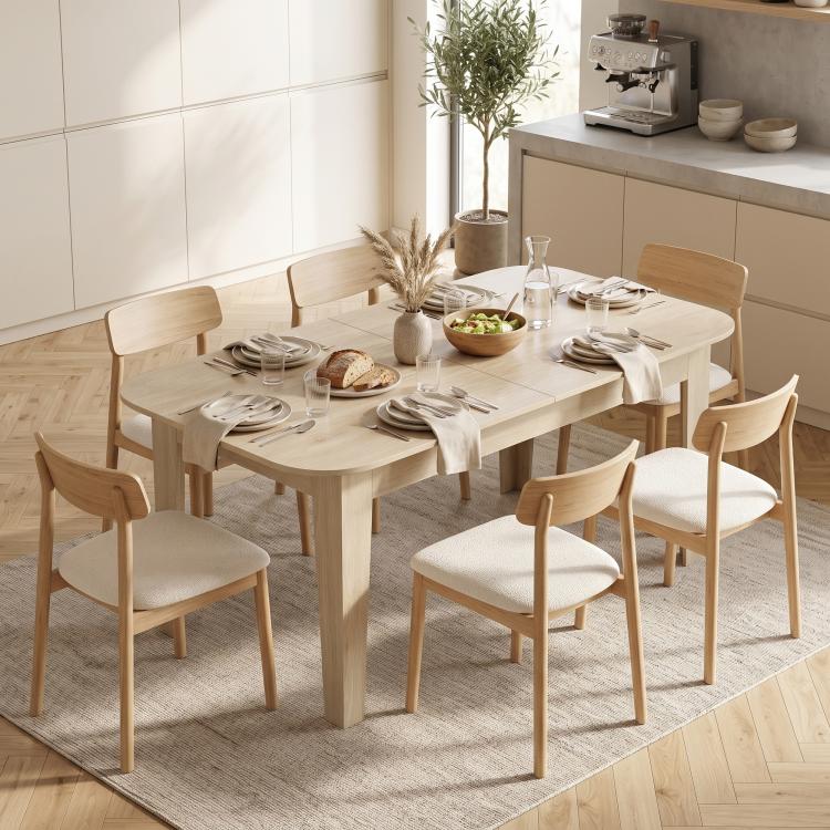 Light oak oval dining table with chairs set up for everyday dining in a bright room