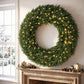 Green pine Christmas wreath with warm white LED lights, centered on wall