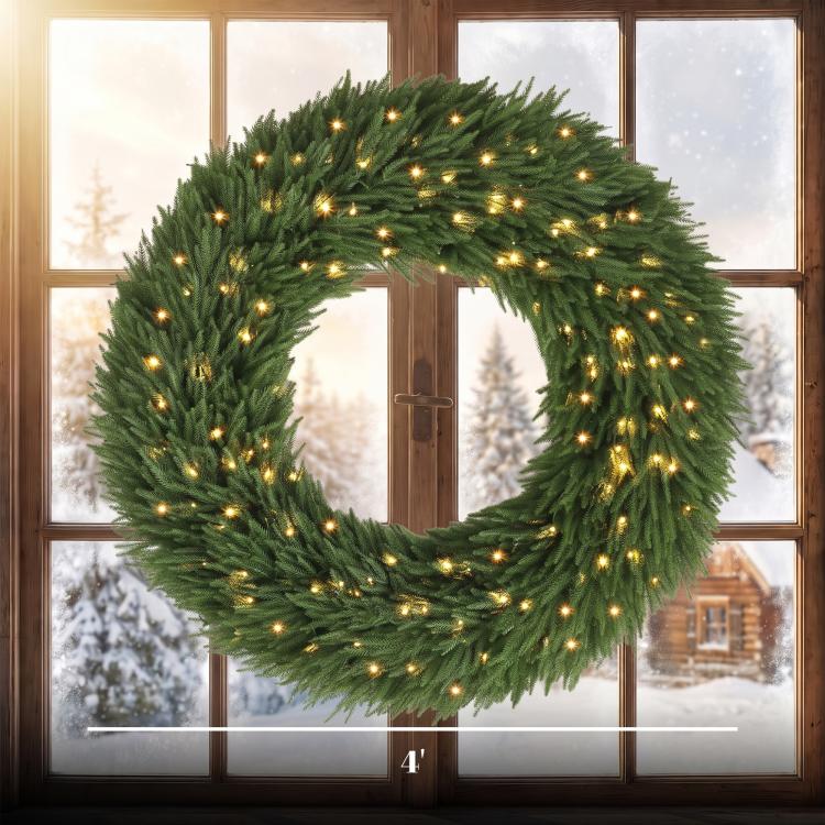 Green pre-lit pine wreath with warm white LED lights, shown in front of windows