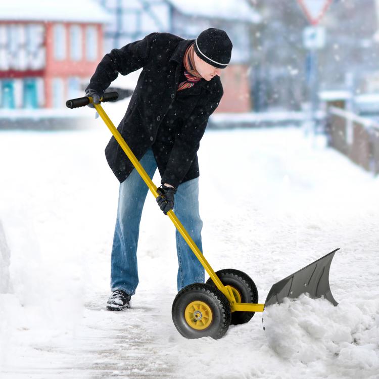 Yellow rolling snow shovel pushing snow with black angled blade and 10-inch wheels