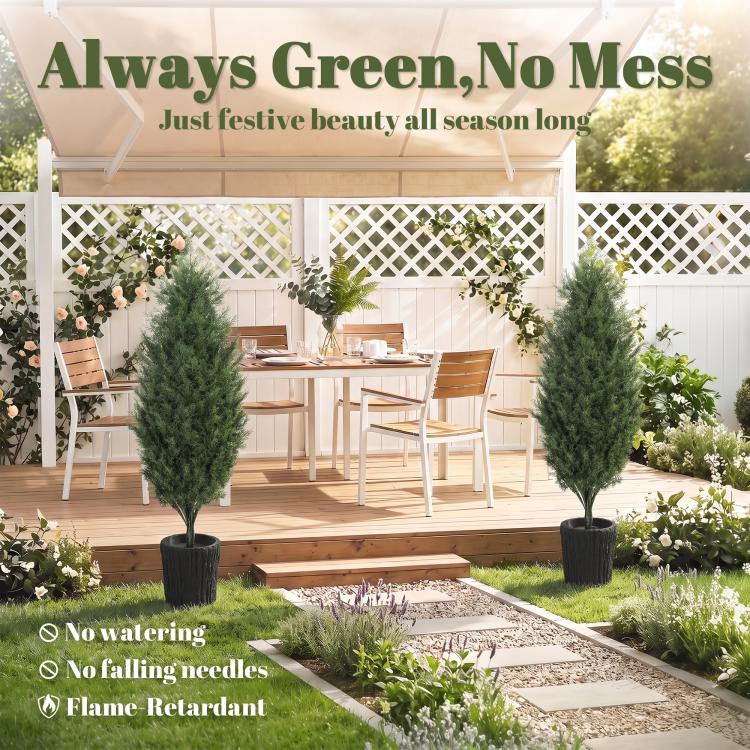 Two faux cedar mini trees in black textured pots on a patio garden walkway