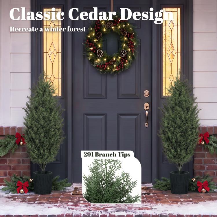 Two faux cedar trees in black textured pots beside a front door with wreath