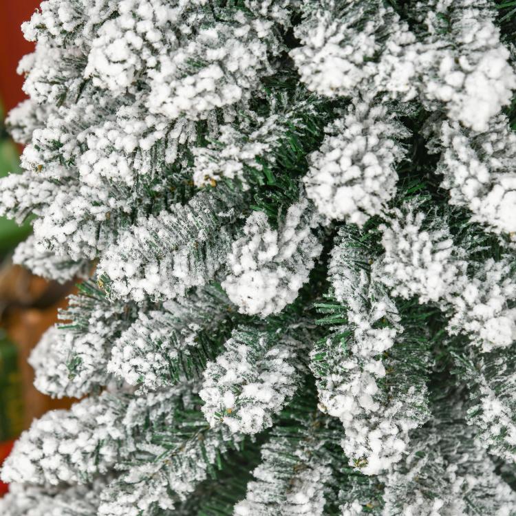 Snow-flocked slim artificial Christmas tree with dense green needles