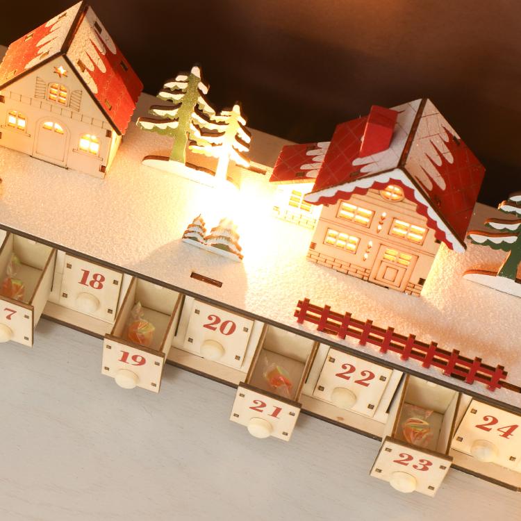 Wood-effect Christmas advent calendar with numbered drawers and lit house village display