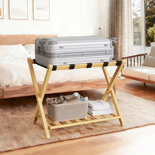 Folding bamboo luggage rack with black straps and lower shelf, holding a gray suitcase