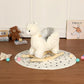 White plush alpaca rocking toy on circular mat with wooden rocker base
