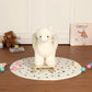White plush alpaca rocking ride-on toy standing on wooden base on dotted mat