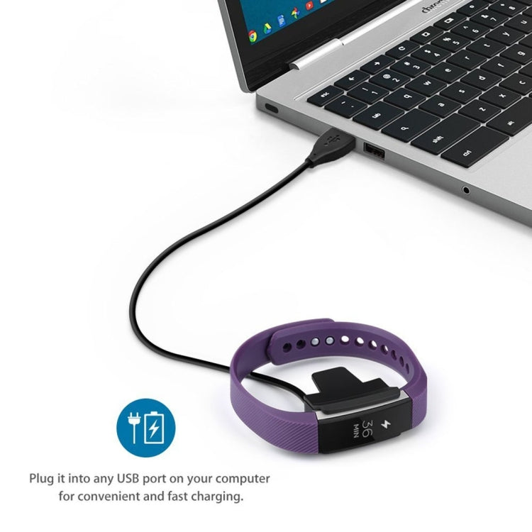 USB charging cable connected to a purple Fitbit Alta band and charging clip