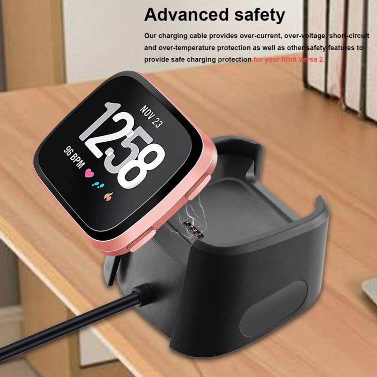 Black charging dock stand charging a smartwatch on a wooden table